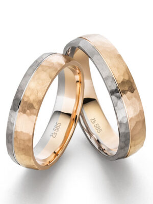Eheringe aus zwei verschiedenen Metallen mit gehämmerter Oberfläche Zwei Eheringe aus Gold und Silber mit einer gehämmerten Oberfläche, die in einem eleganten Design gestaltet sind.